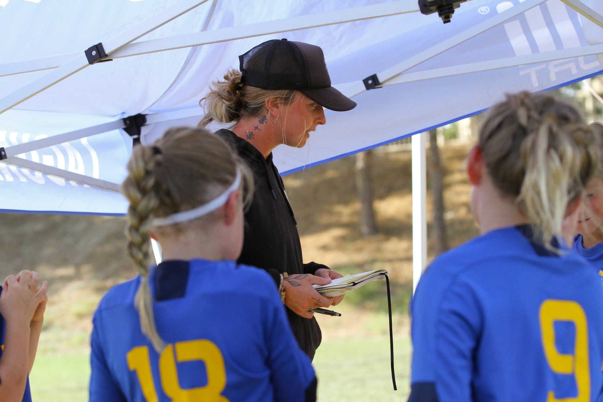Coach Bella reading her notes to her team in a game day huddle