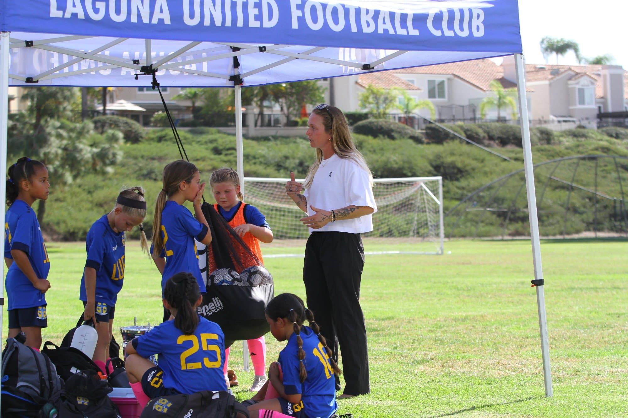 Coach Bella talking with her girls' team under the tent on game day