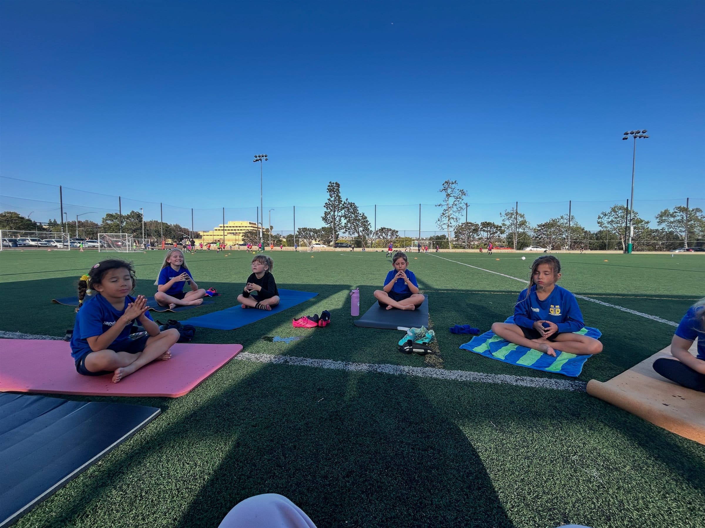 Young athletes sitting and meditating together on the training field